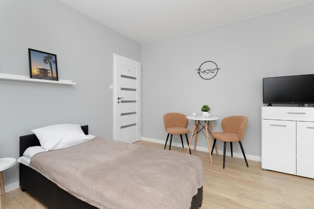 een slaapkamer met een bed en een tafel met stoelen bij Apartment in Gdańsk with 3 Bedrooms, Furnished Balcony and 2 Desks by Rent like home in Gdańsk