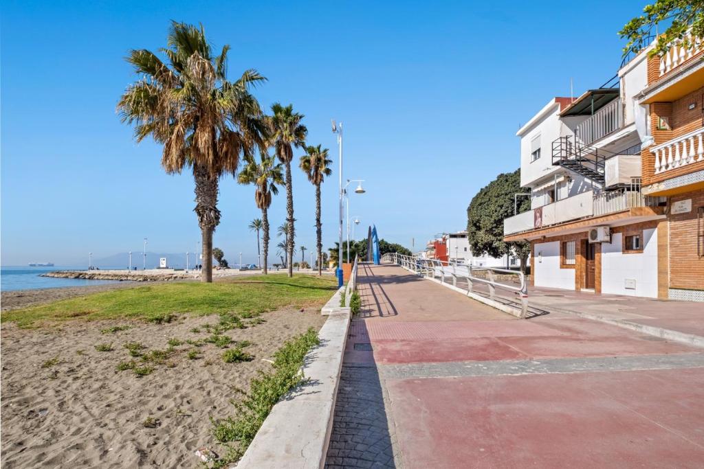 a sidewalk next to a beach with palm trees at Apartamento frente a la playa in Málaga
