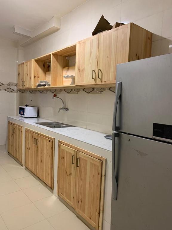 a kitchen with wooden cabinets and a refrigerator at Appartement meublé au virage in Yof