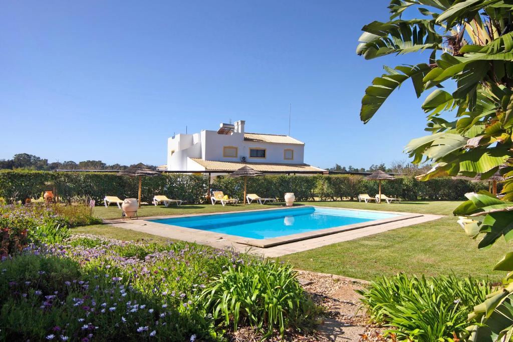 a villa with a swimming pool in a garden at Casa Pimenta Rosa in Alvor