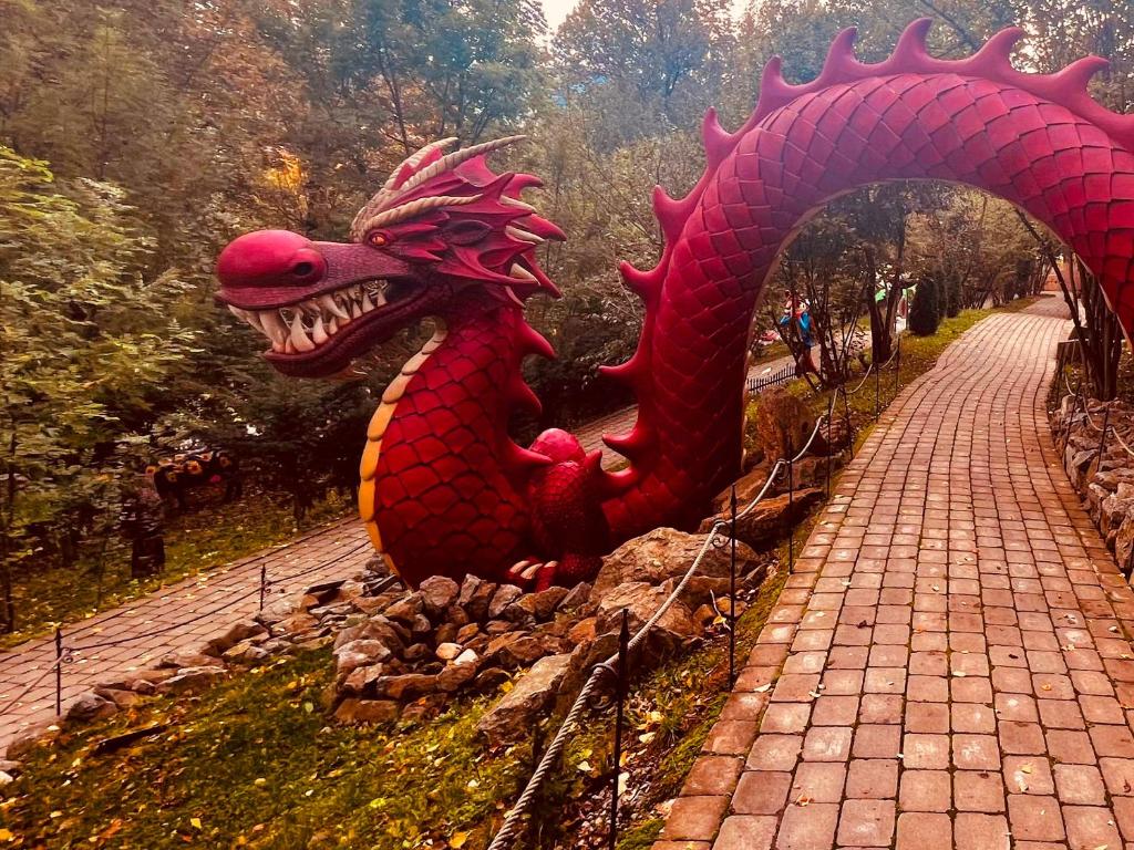 a statue of a red dragon sitting on a path at Zrubový Dom 1 v Panoráma Parku in Nezbudská Lúčka