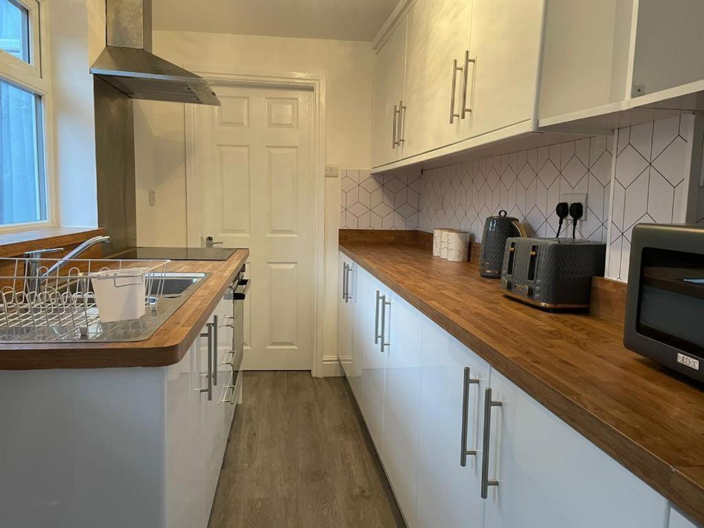ミドルズブラにあるMayfun House by Teeside Uniの白いキャビネット、シンク、電子レンジ付きのキッチンが備わります。
