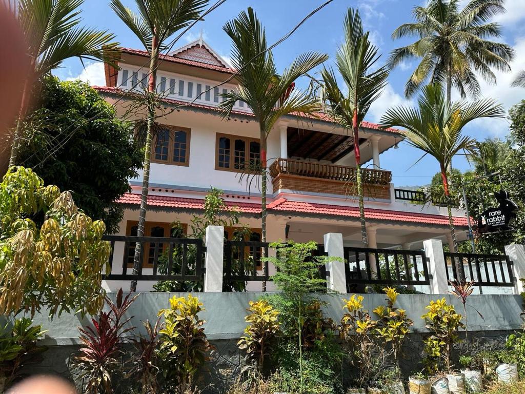 une maison avec des palmiers devant elle dans l'établissement Rare Rabbit Munnar, à Anachal