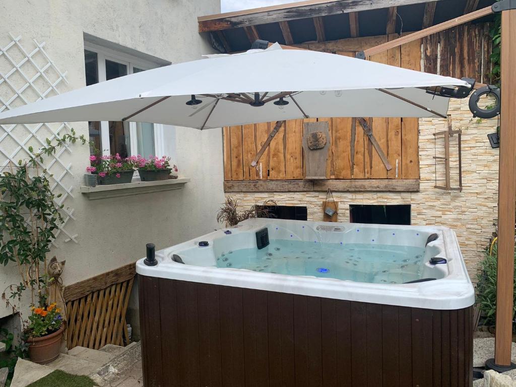 - un bain à remous avec un parasol sur la terrasse dans l'établissement GÎTE REDROOSTER HOME - 160m2, 4 ch, 2 sdb, fibre, parking, sauna, bain à remous, à Theys
