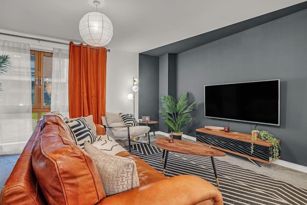 a living room with a leather couch and a flat screen tv at Sleek City Living with Bicocca Stays in Aberdeen