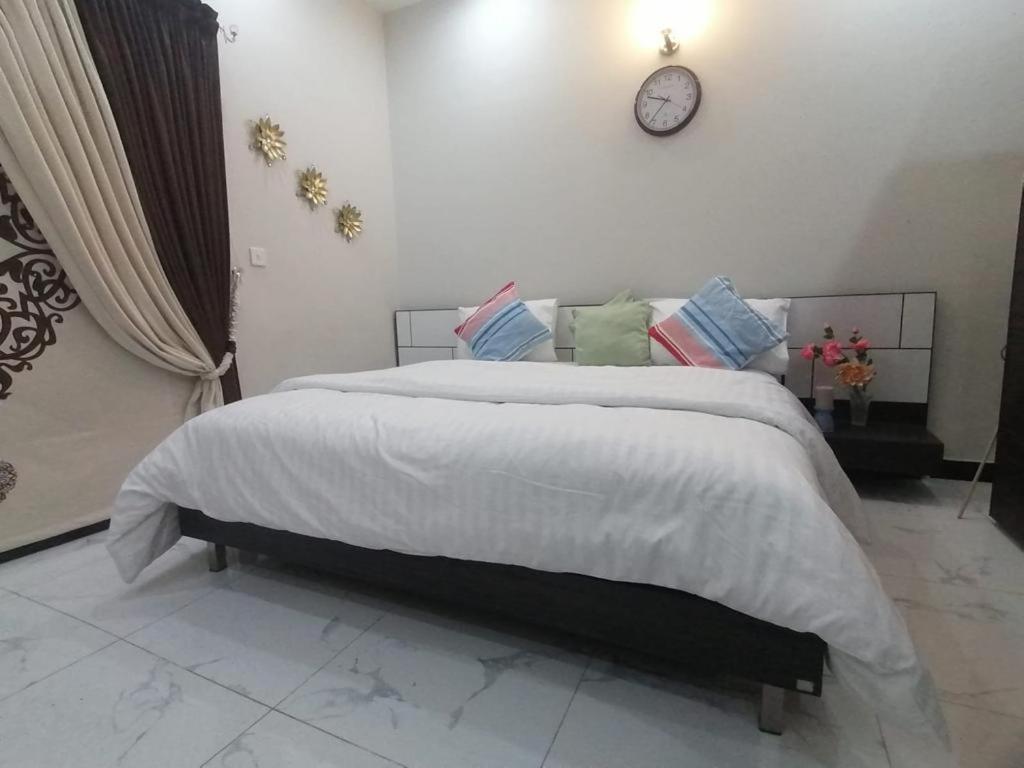 a bedroom with a large bed with a clock on the wall at SM Dream Lodges Luxury Stay in Islamabad