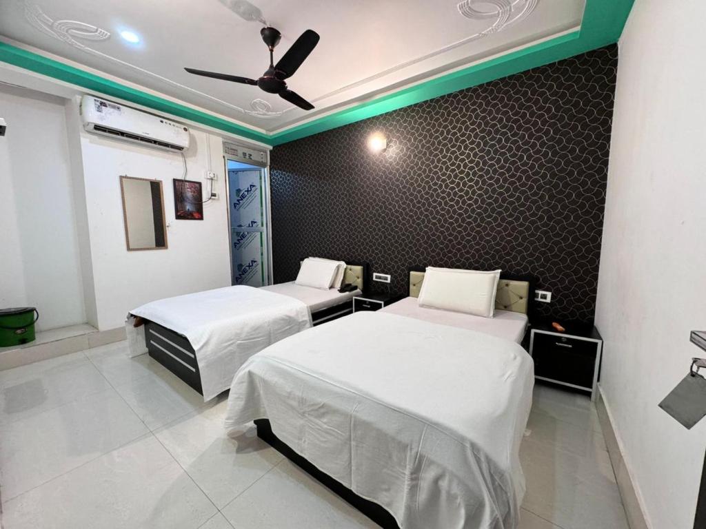 a room with two beds and a ceiling fan at Hotel Nalanda Inn Bihar in Nalanda