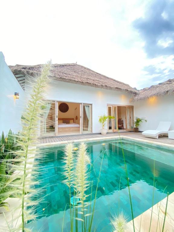 a villa with a swimming pool in front of a house at Mimpi Villa - Gili Air in Gili Islands
