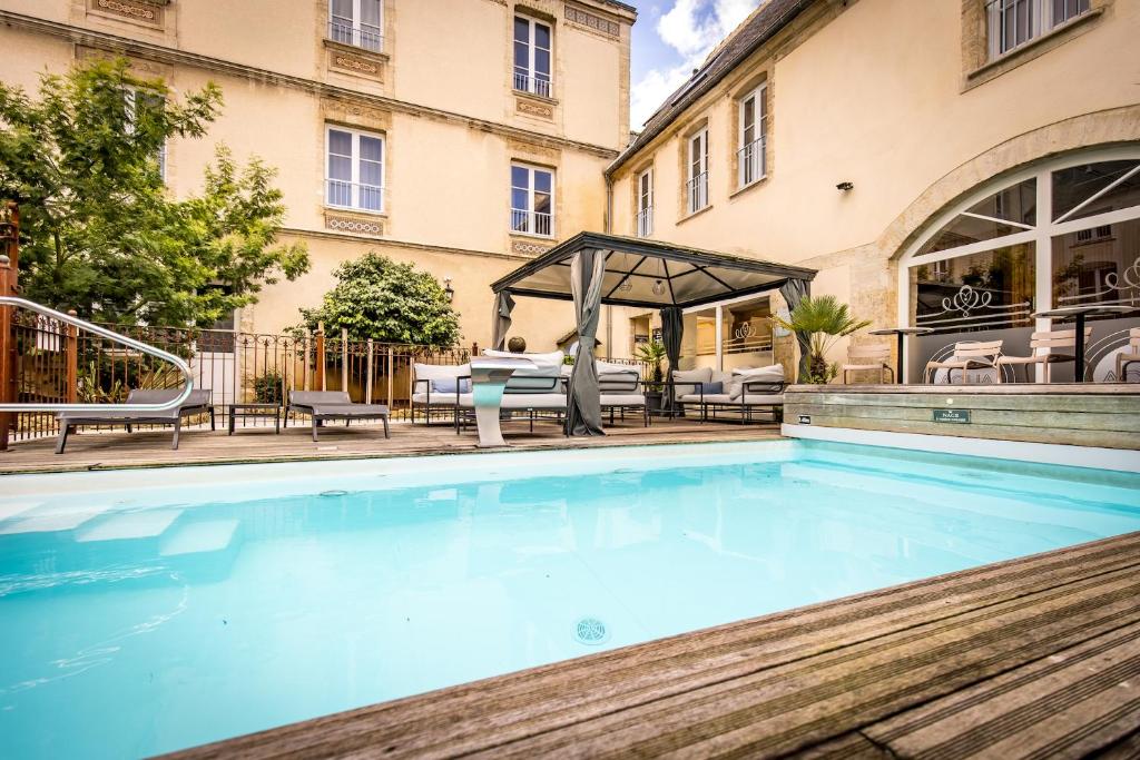 a swimming pool in front of a building at Hôtel De Brunville & Spa in Bayeux