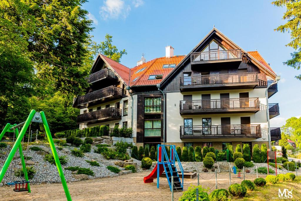 una casa con parque infantil frente a un edificio en Panorama Gór, en Szklarska Poręba