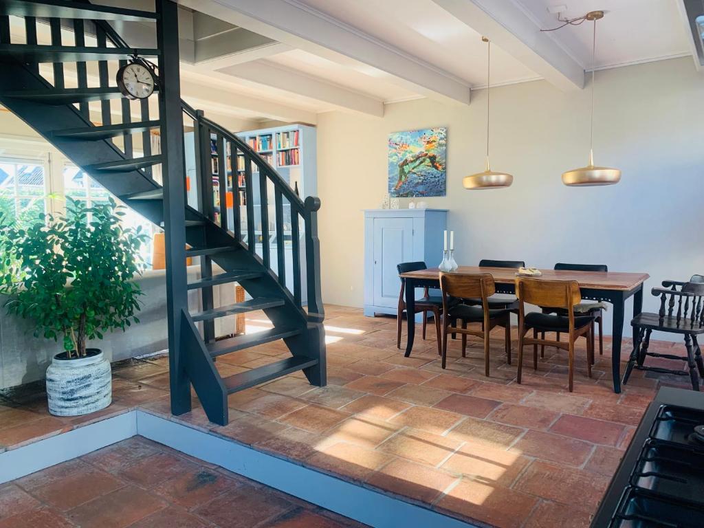 a dining room with a staircase and a table with chairs at Topzomer in Sleat in Sloten
