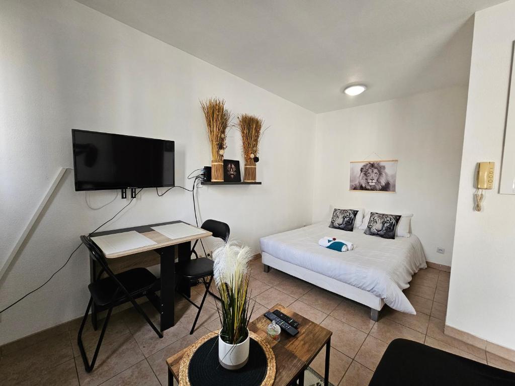 a room with a bed and a table and a tv at A112 Appartement Proche Disneyland Paris in Montévrain