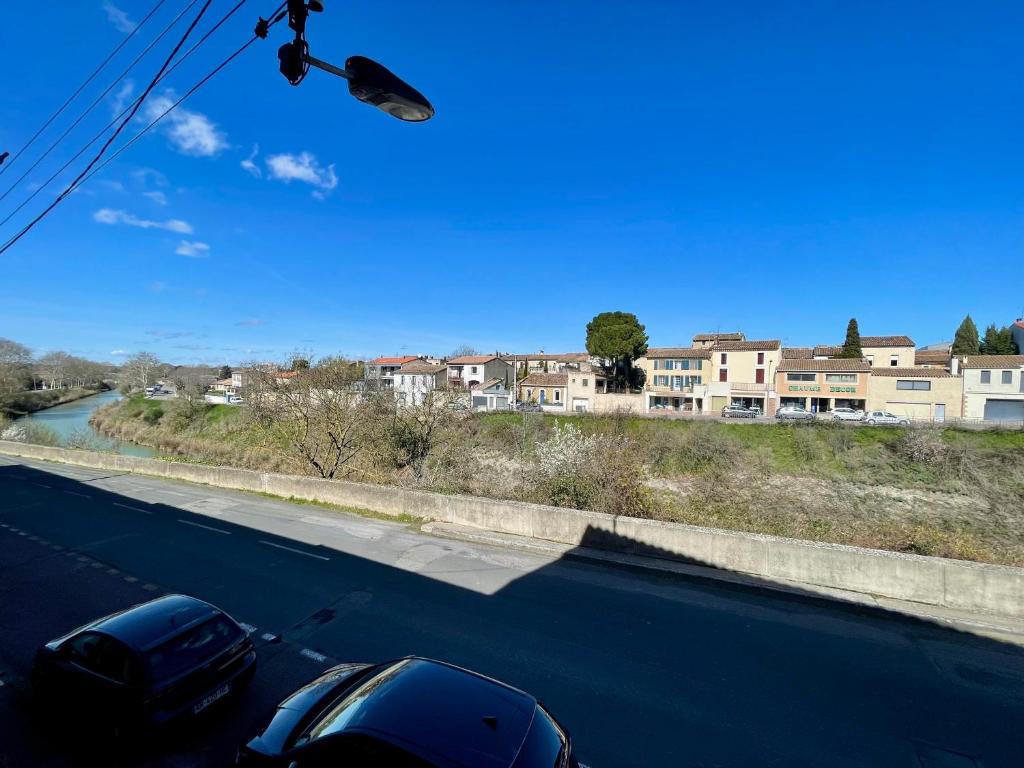 カルカソンヌにあるLes Appartements - Canal du Midiの背景に建物を配置した道路に停車した車2台