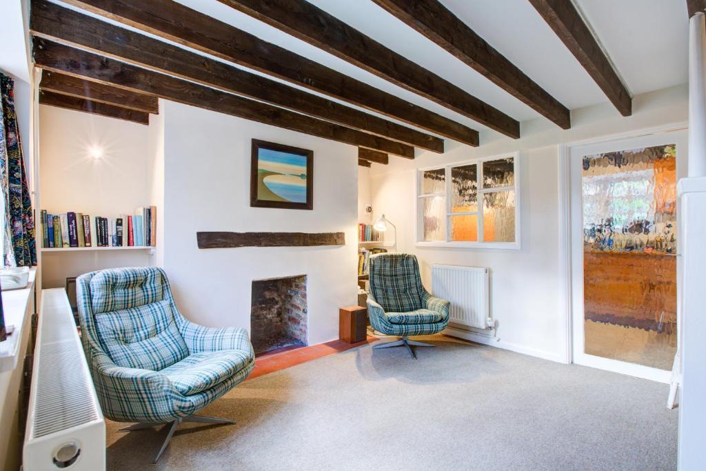 two chairs in a living room with a fireplace at Charming Hilltop Cottage with Panoramic Views in East Worldham