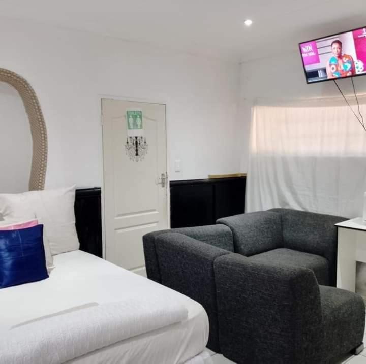 a hotel room with a bed and a couch and a tv at Mokopane at Freedom City Lodge in Mokopane