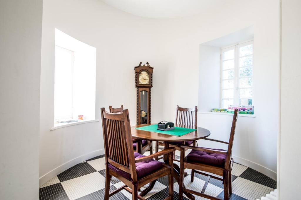 a dining room with a table and a grandfather clock at Gîte Château de Seguin in Lignan-de-Bordeaux
