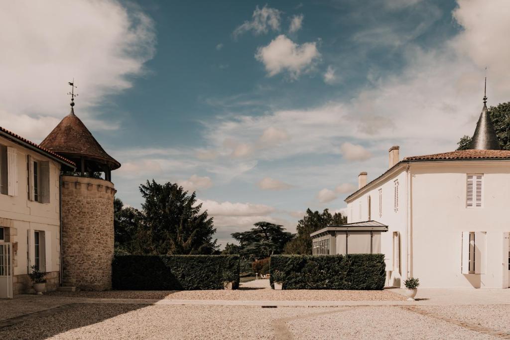 a white building with a turret on the side of it at Gîte Château de Seguin in Lignan-de-Bordeaux