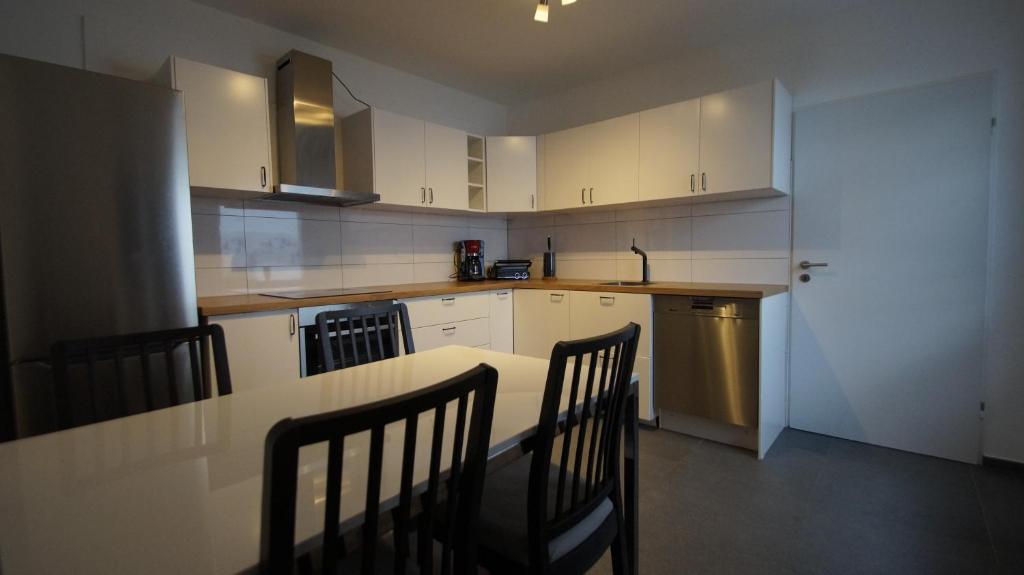 a kitchen with white cabinets and a table and chairs at Ferienwohnung Best Apartments Leverkusen 2 in Leverkusen