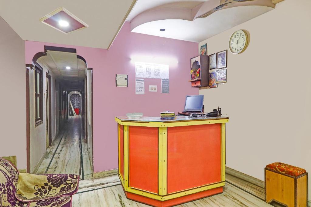 Habitación con escritorio y reloj en la pared en Collection O Hotel Shree Narayan Regency, en Kānpur
