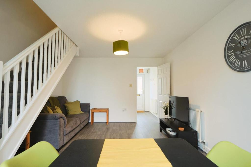 a living room with a couch and a clock on the wall at Broadcroft two bedroom house in North Bristol in Bristol