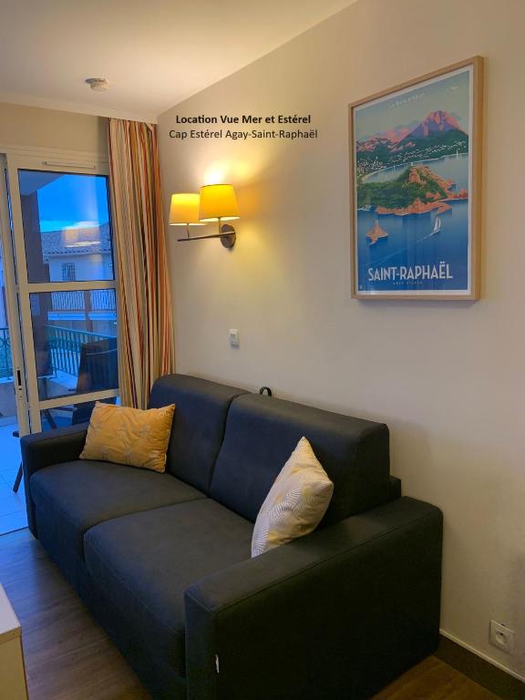 a living room with a couch and a picture on the wall at &quot;Location Vue MER et ESTEREL&quot;, Cap Estérel Agay-Saint Raphaël, T2, piscines, parking, wifi in Saint-Raphaël
