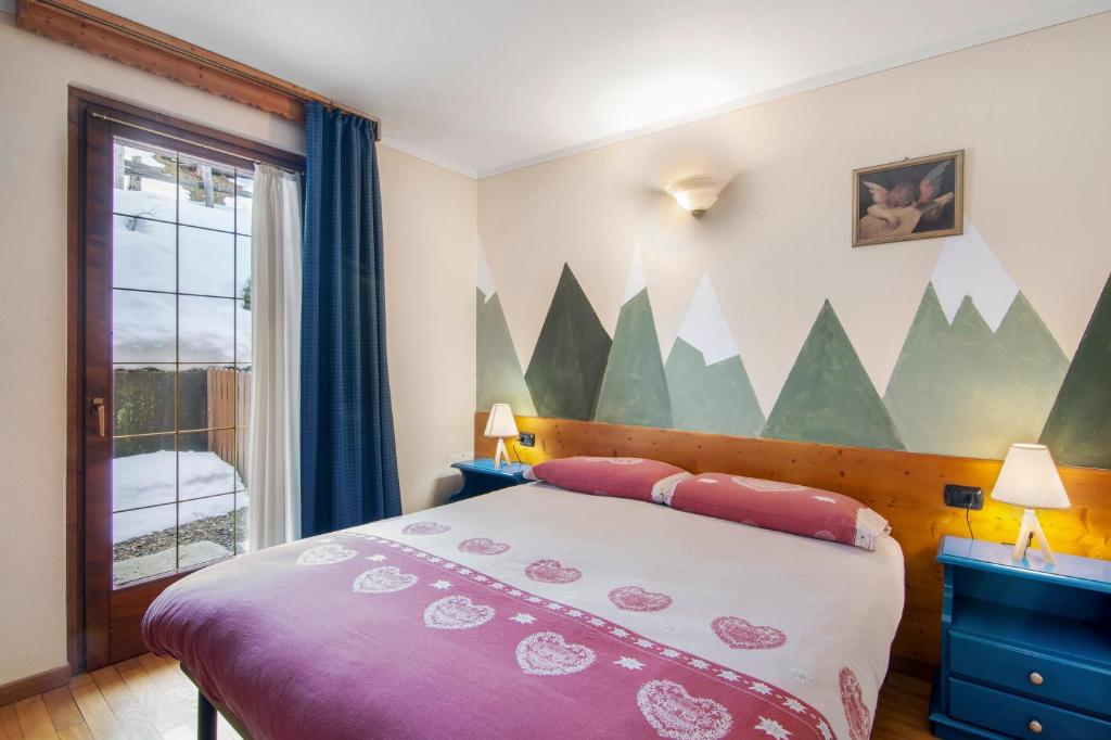 a bedroom with a bed with a mountain mural on the wall at Residence Larice Bianco App n3 in Campodolcino