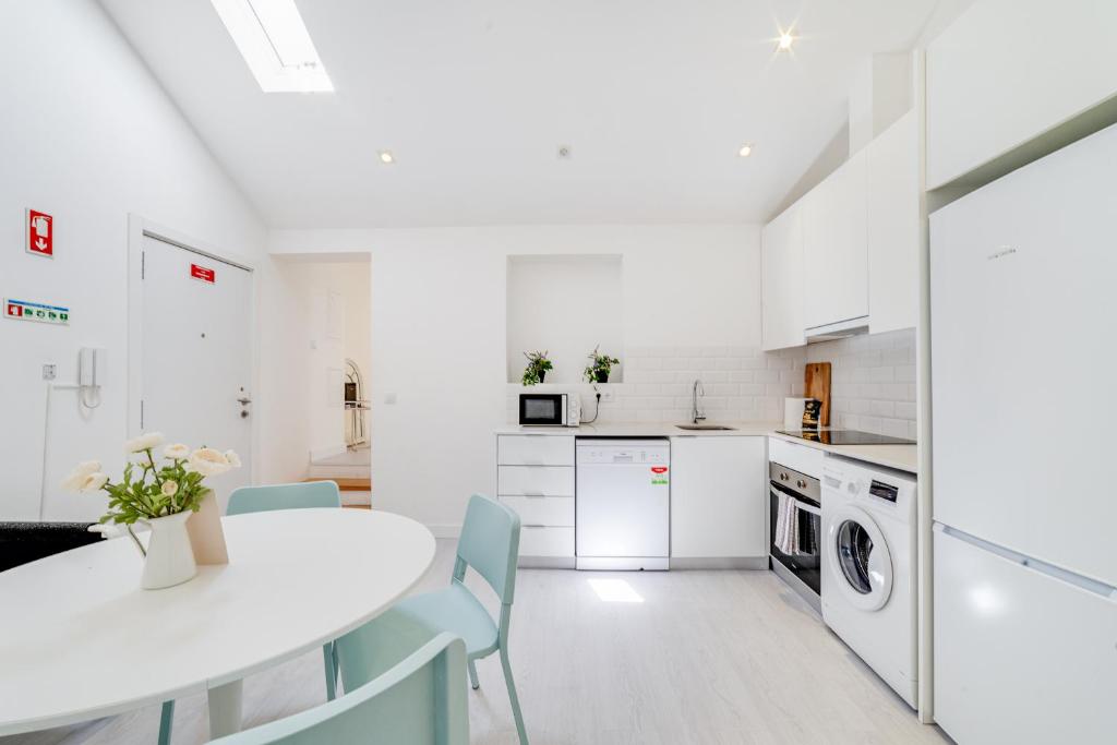 a white kitchen with a white table and chairs at Alcantara Charm 3BR Apartments in Lisbon