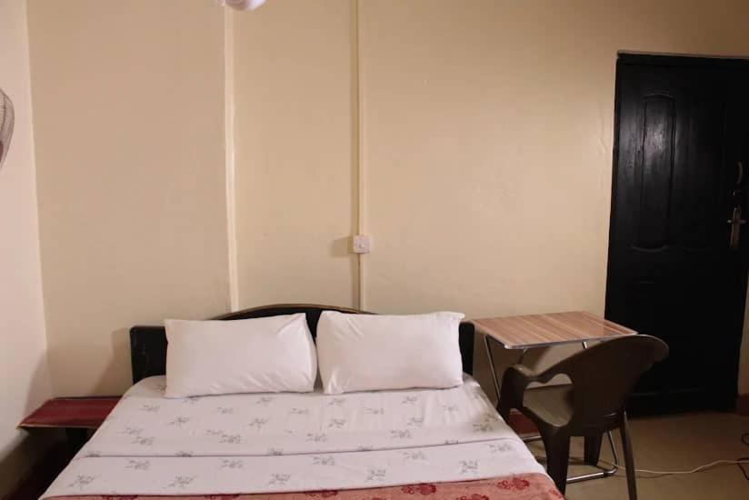 a bed with two pillows and a table in a room at Agabet Hotel - Mbale in Mbale