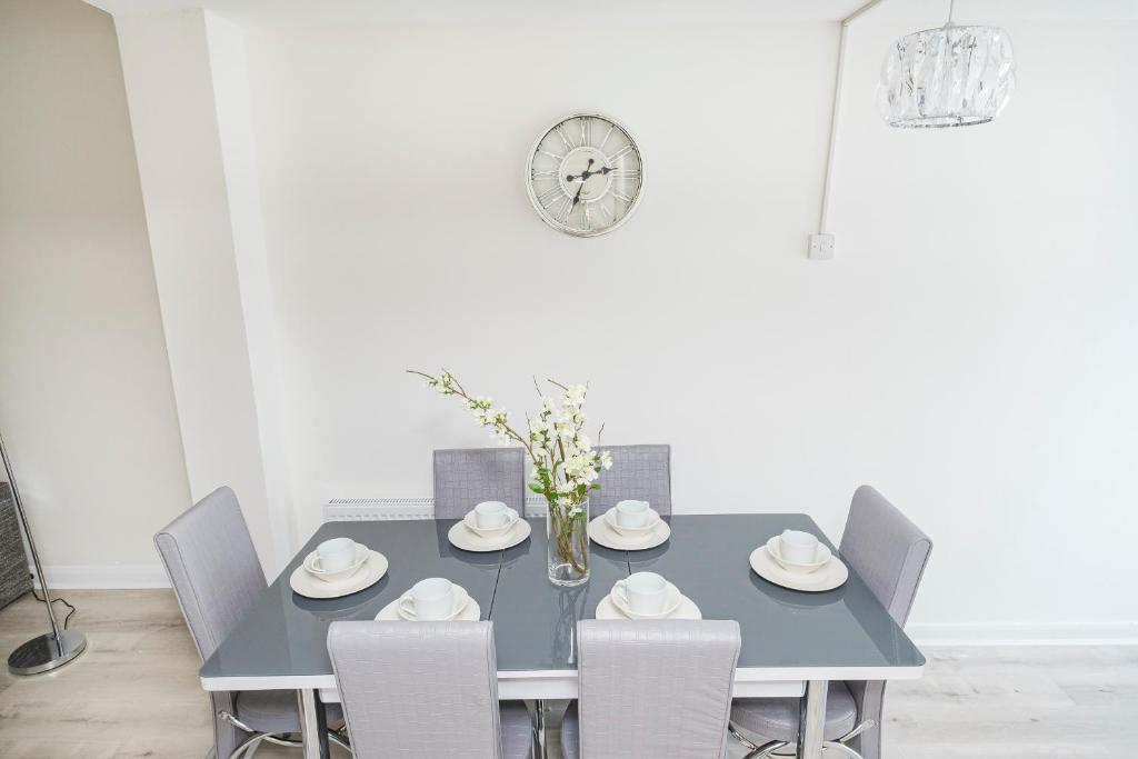 雷恩漢姆的住宿－Heads-On-Beds Rainham Essex - 4Bedrooms with Garden，蓝色的餐桌、椅子和时钟