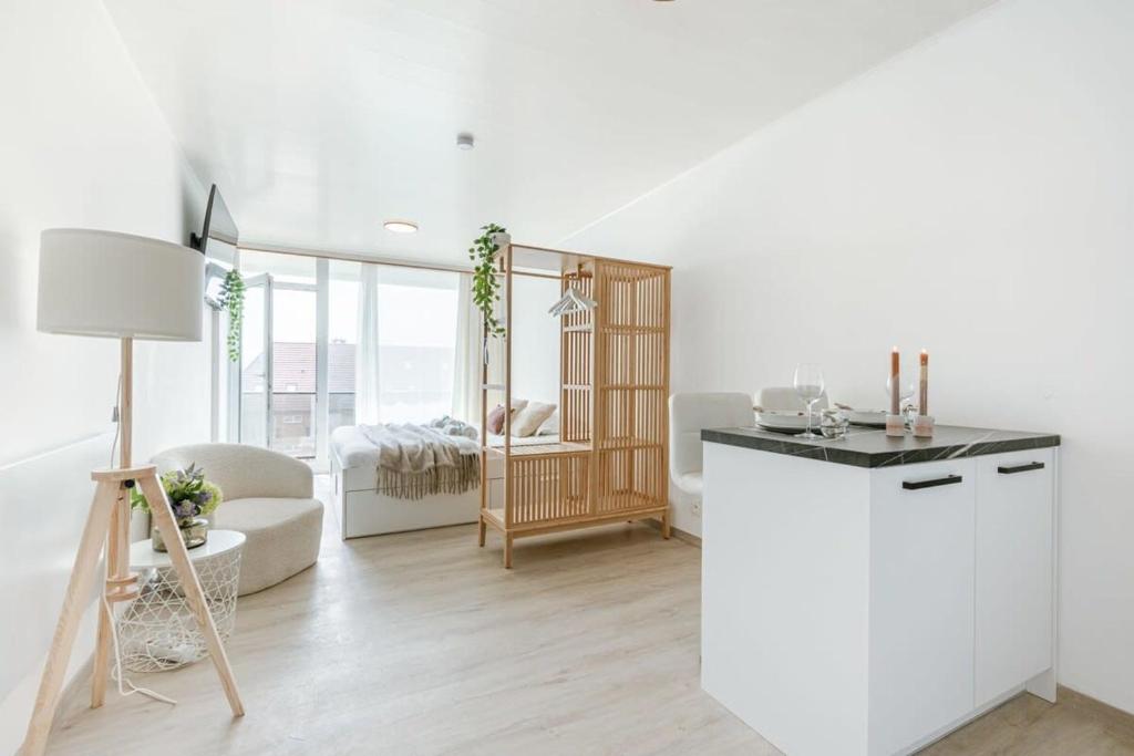 een witte keuken met een woonkamer met een tafel bij Cosy studio near the beach in Oostende