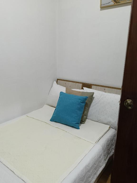 ein weißes Bett mit einem blauen Kissen darauf in der Unterkunft AJ Transient House in Gairan