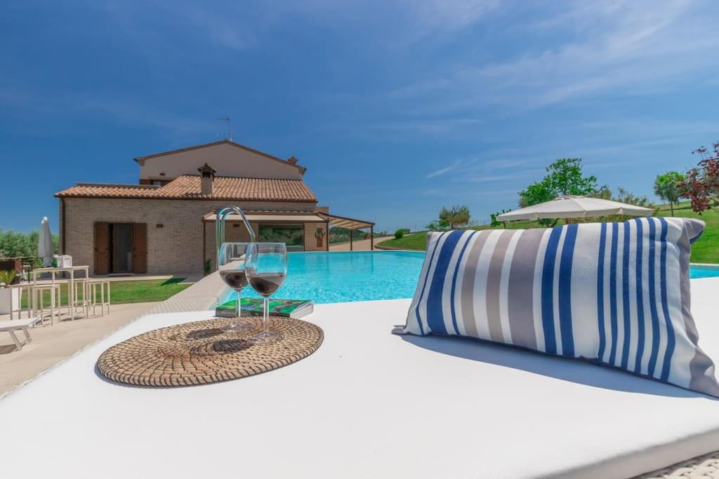 een tafel met een glas wijn en een kussen bij [Villa Luxury] Piscina BBQ Free Parking in Capodarco