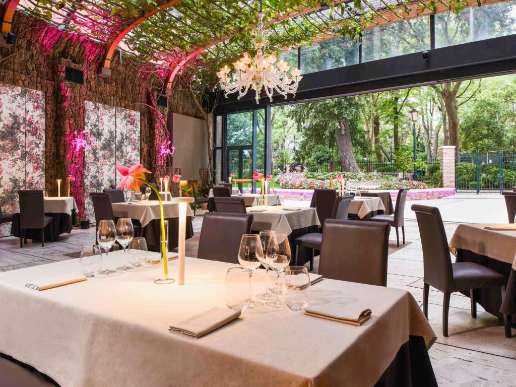 a restaurant with white tables and chairs and windows at Hotel Papadopoli Venezia - MGallery Collection in Venice