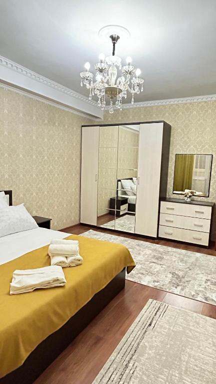 a bedroom with a large bed and a chandelier at Апартаменты посуточно in Atyrau