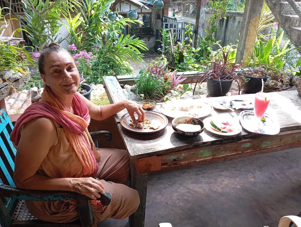 a woman sitting at a table with a plate of food at SD3M ART GALLERY Villa in Dickwella