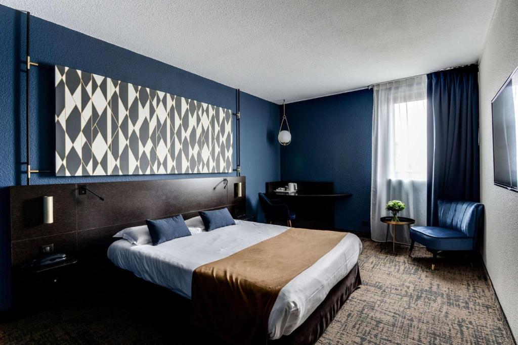 a bedroom with a large bed and a blue wall at Brit Hotel Du Stade Rennes Ouest in Rennes