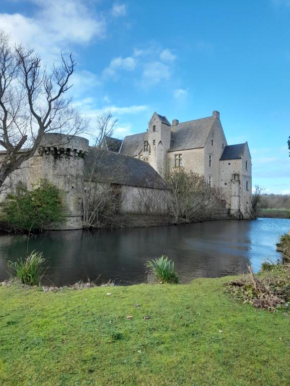 um velho castelo sentado ao lado de um rio em 6, route de Maisons Manoir d'Argouges em Vaux-sur-Aure