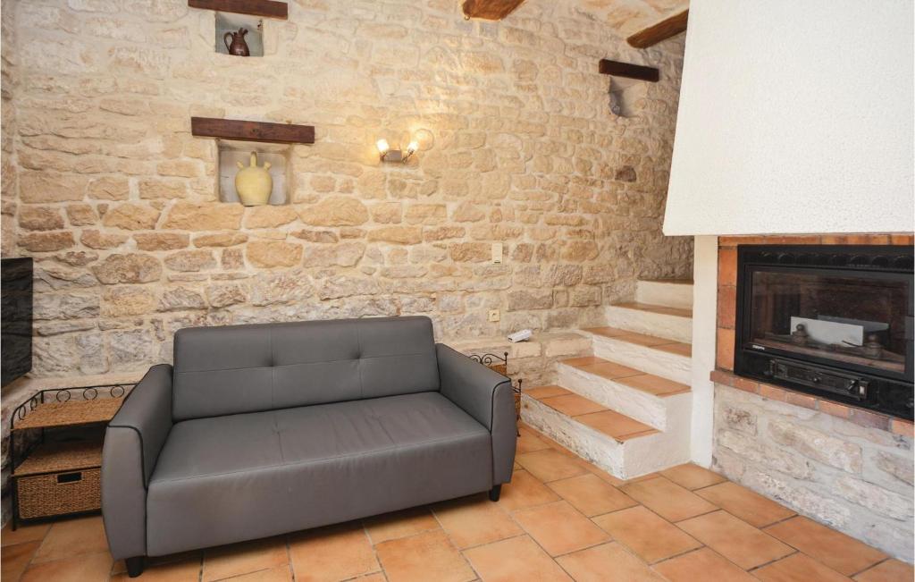 a leather couch in a living room with a stone wall at Amazing Home In Barjac With 3 Bedrooms, Wifi And Outdoor Swimming Pool in Barjac