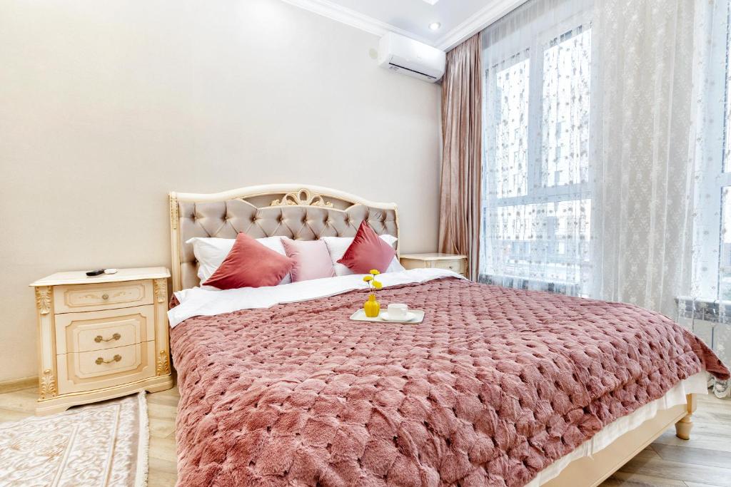 a bedroom with a large bed with a large window at Апартаменты возле ЭКСПО in Astana