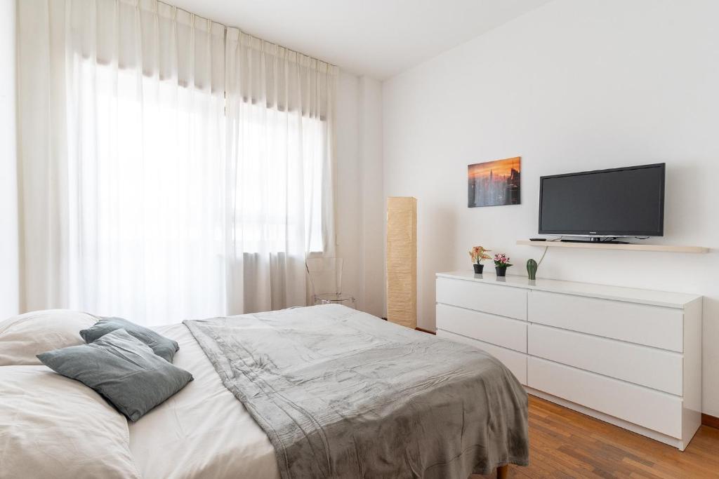 a white bedroom with a bed and a tv at Pane&Pomodoro Apartment in Bari