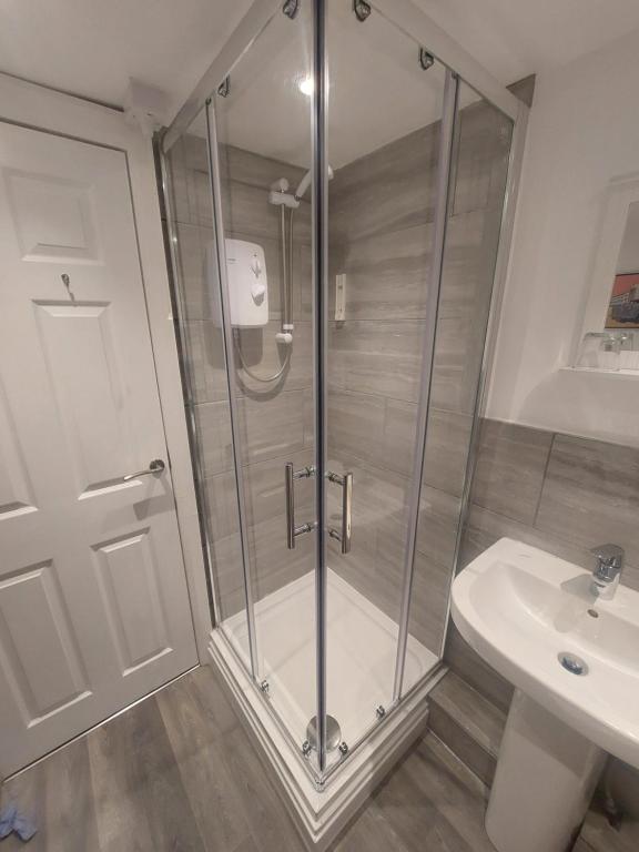 a shower with a glass door next to a sink at Basement Studio by the Bay in Morecambe