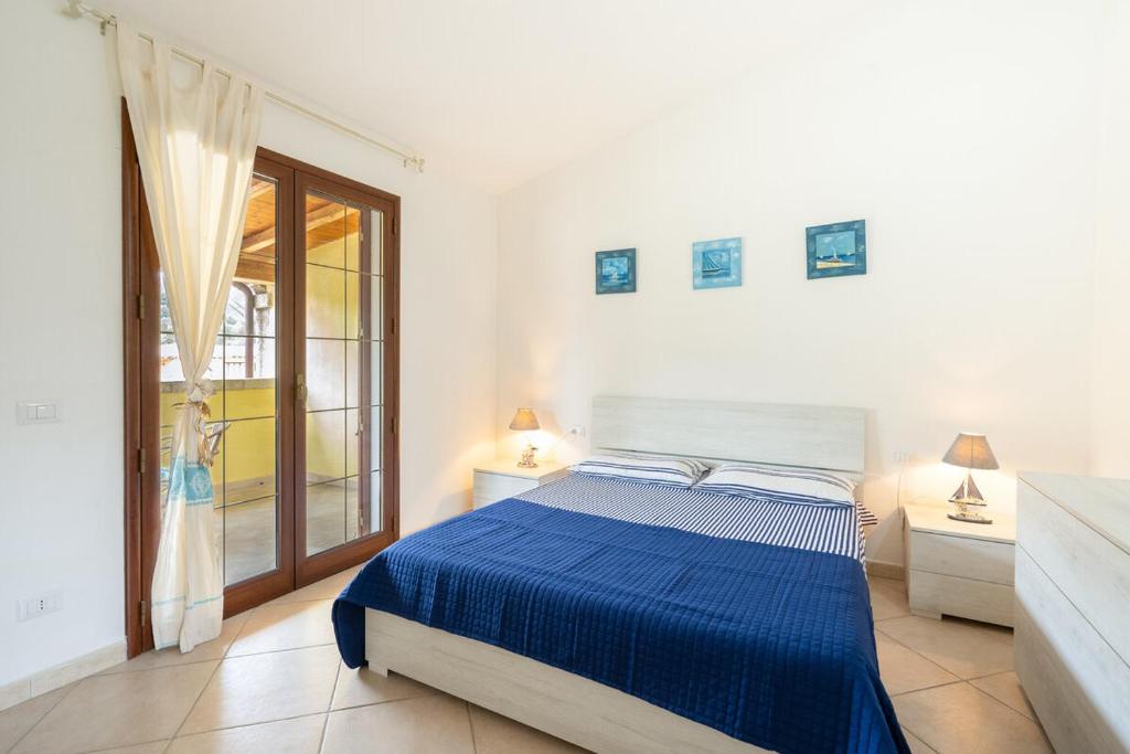 a white bedroom with a blue bed and a window at Angel Village in San Teodoro