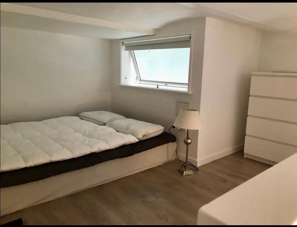 um pequeno quarto com uma cama e uma janela em Small cosy appartment em Skanderborg