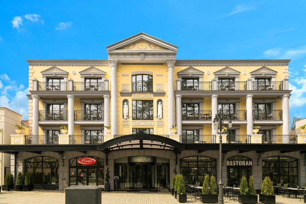 a yellow building with balconies on a street at A Hoteli - Hotel Park in Vrnjačka Banja