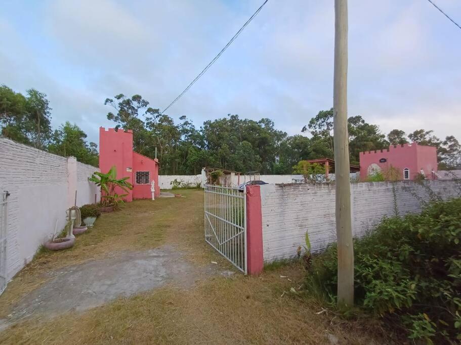 płot przed budynkiem z różowymi domami w obiekcie Casa do Mato II w mieście São Lourenço do Sul