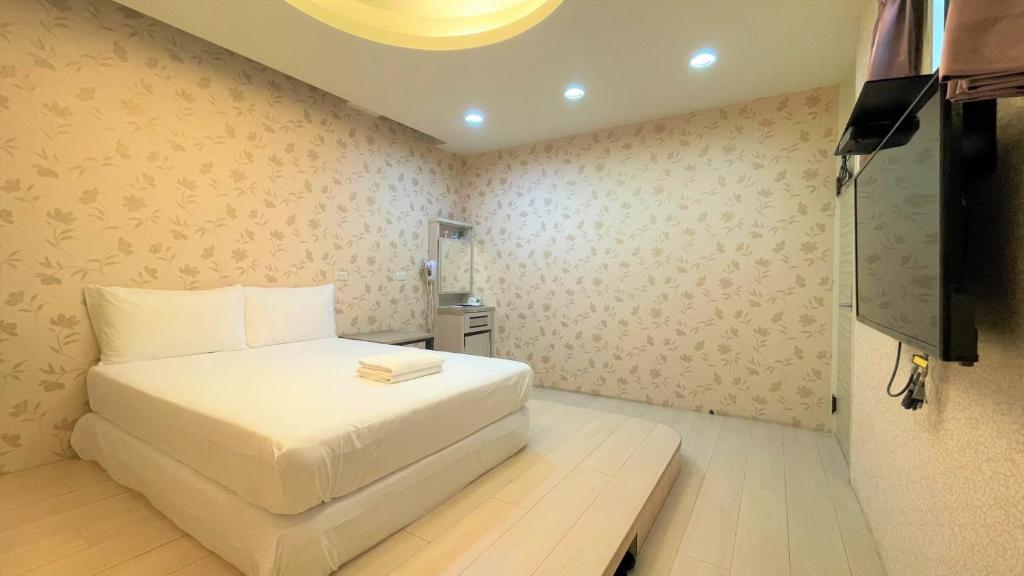 um quarto com uma cama branca e uma televisão de ecrã plano em 逢甲馨宿 em Hsia-shih-pi