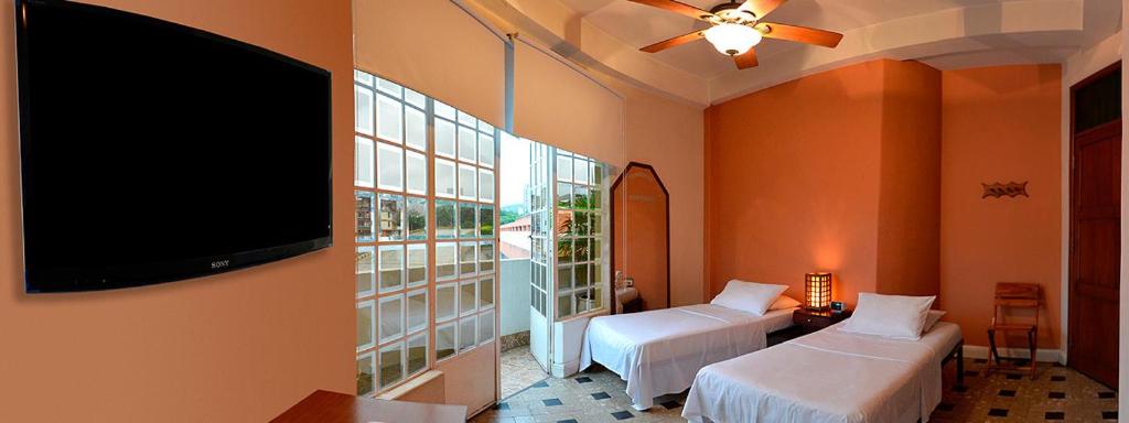 Un dormitorio con dos camas y un televisor de pantalla plana. en Hotel Savoy, en Cali