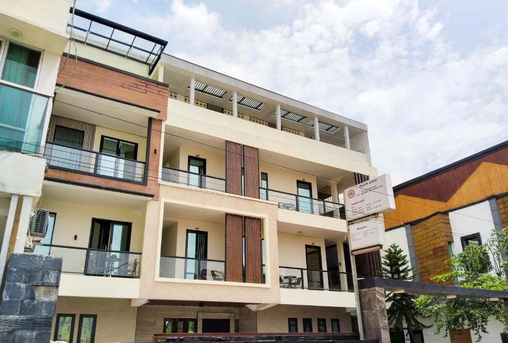 un edificio de apartamentos con balcones y letreros de la calle en Yayah Guest House Syariah by Cocotel en Bubulak 3