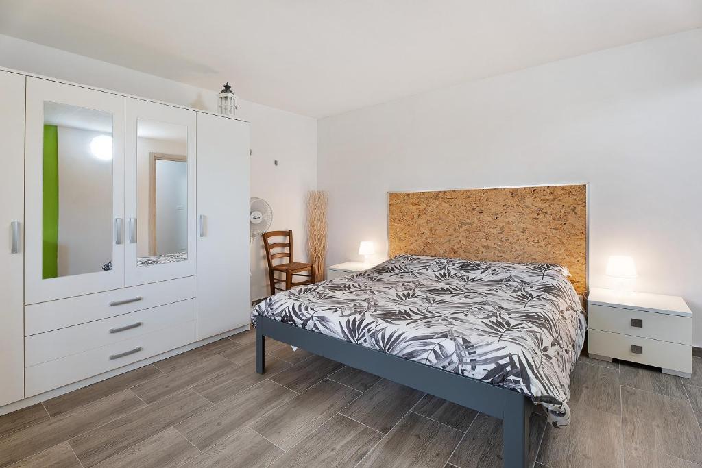 a white bedroom with a bed and a chair at Bambù in Arona