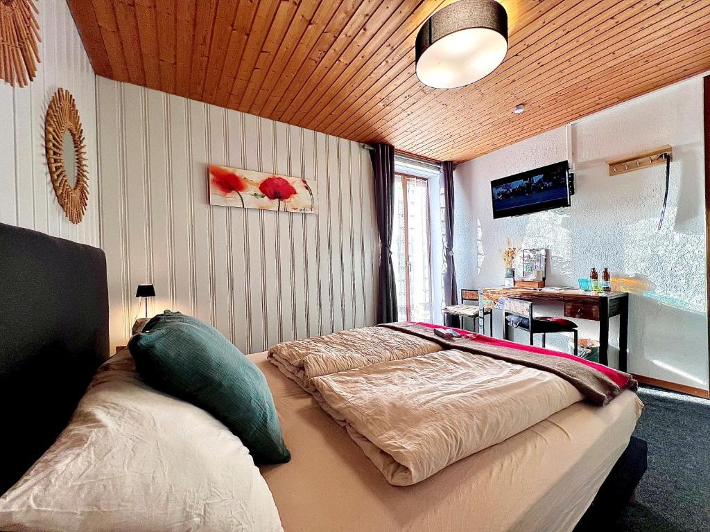 a bedroom with a bed and a desk in it at Hôtel Restaurant Les Cernets Swiss-Lodge SSH in Les Verrières